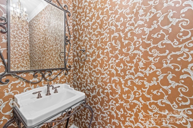 bathroom featuring crown molding, an inviting chandelier, and sink