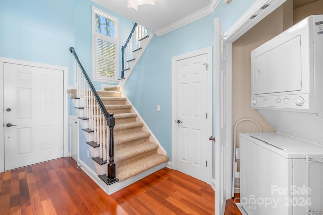 laundry area featuring crown molding, wood-type flooring, and stacked washer and clothes dryer