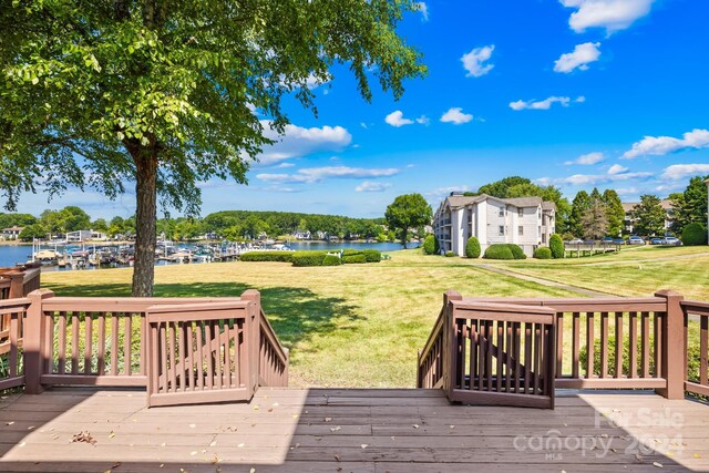 wooden terrace with a water view and a yard