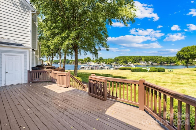 wooden terrace with a water view and a yard