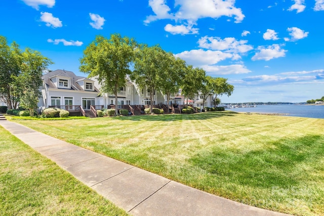 view of home's community with a water view and a yard