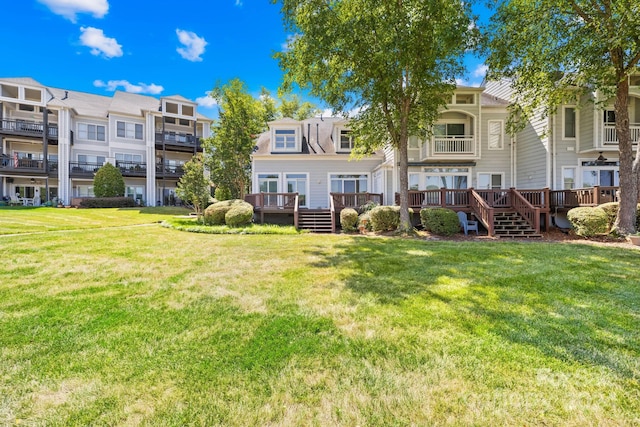 rear view of property featuring a yard, a deck, and a balcony