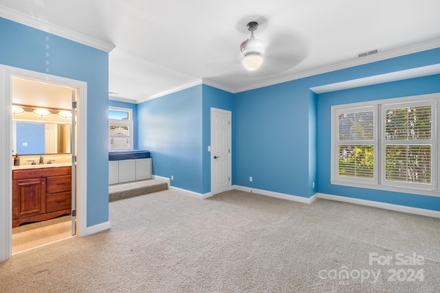 unfurnished bedroom featuring crown molding, connected bathroom, light carpet, and ceiling fan