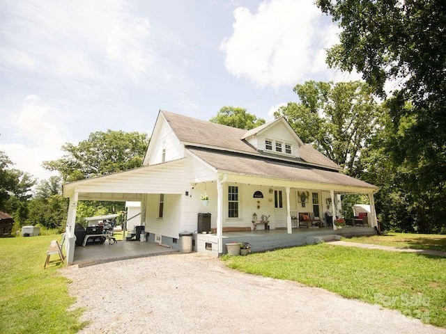 country-style home featuring a front yard, covered porch, and a carport