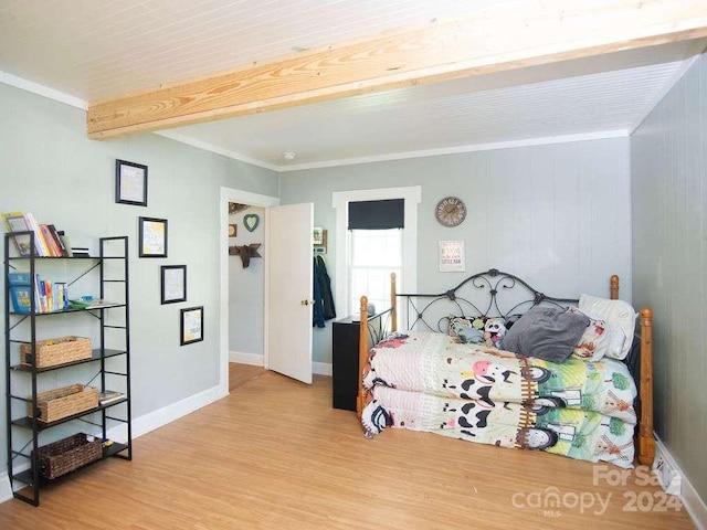 bedroom featuring ornamental molding, light wood-type flooring, beam ceiling, and wood walls