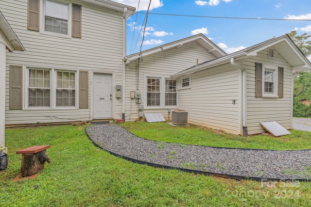 rear view of property featuring cooling unit and a yard