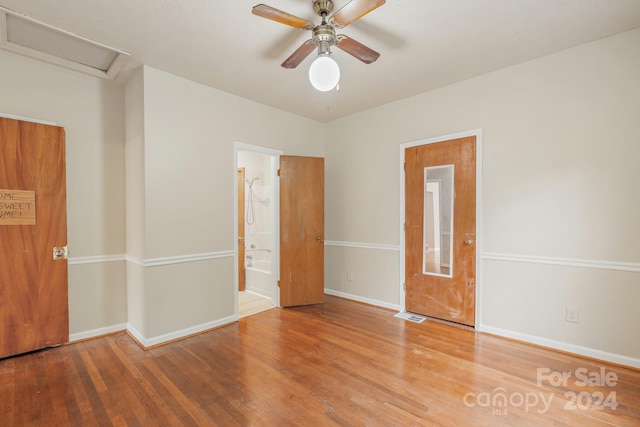 unfurnished bedroom with ensuite bathroom, ceiling fan, and hardwood / wood-style floors