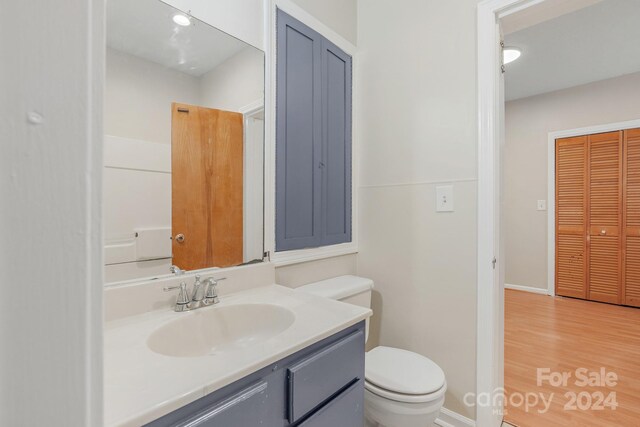 bathroom with hardwood / wood-style flooring, toilet, and vanity