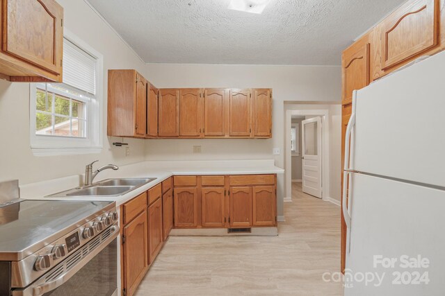 kitchen with light hardwood / wood-style flooring, sink, a textured ceiling, stainless steel range with electric stovetop, and white fridge