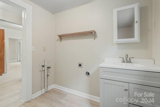 laundry room featuring light hardwood / wood-style floors, sink, cabinets, and hookup for an electric dryer