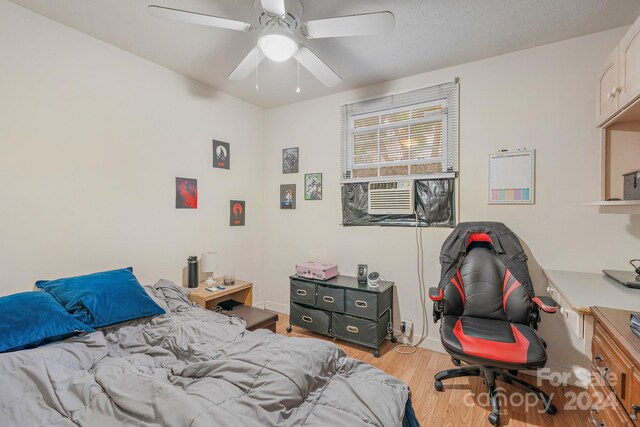 bedroom featuring cooling unit, ceiling fan, and light hardwood / wood-style flooring