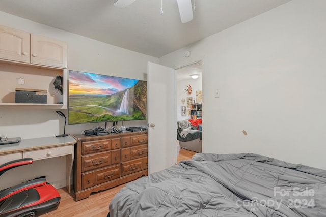 bedroom with ceiling fan, light wood-type flooring, and built in desk