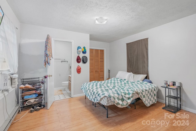 bedroom with light wood-type flooring, a closet, connected bathroom, and a textured ceiling