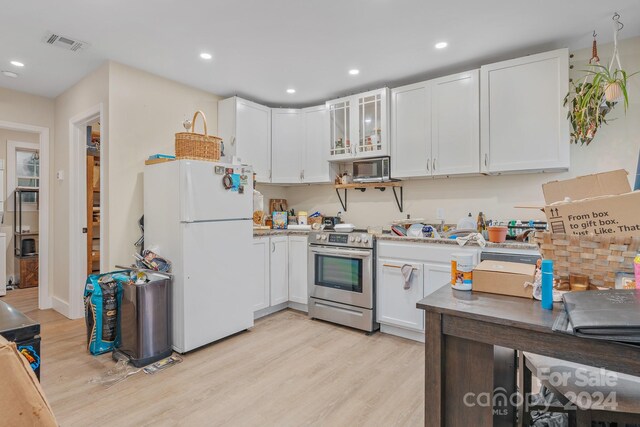 kitchen with white cabinets, white fridge, light wood-type flooring, and electric stove