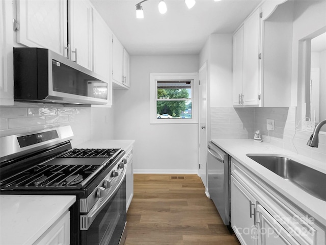 kitchen with sink, appliances with stainless steel finishes, white cabinets, backsplash, and dark wood-type flooring