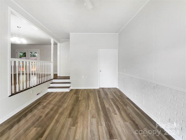 empty room with a notable chandelier and dark hardwood / wood-style flooring