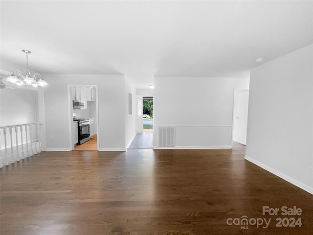 unfurnished living room with a notable chandelier and dark hardwood / wood-style floors