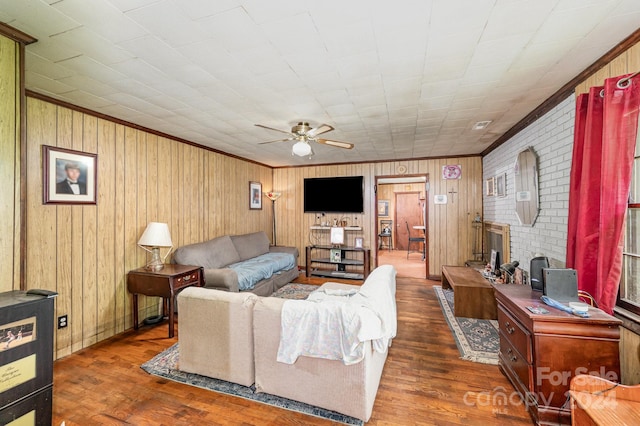 living room featuring brick wall, ceiling fan, wood walls, dark wood-type flooring, and ornamental molding