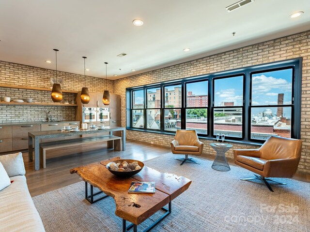 living room featuring sink, brick wall, and wood-type flooring