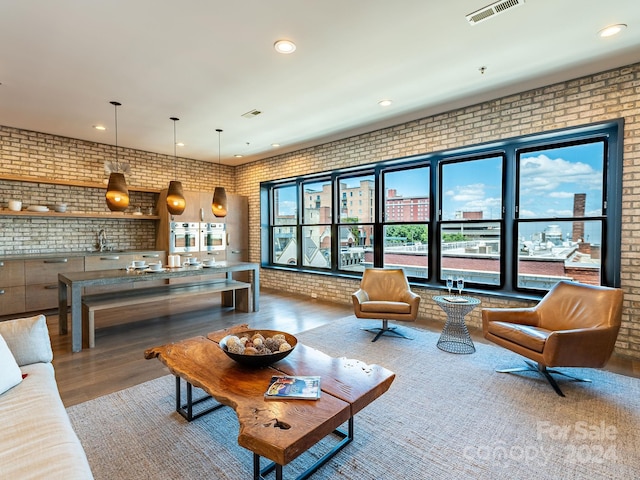 living room with brick wall and hardwood / wood-style flooring