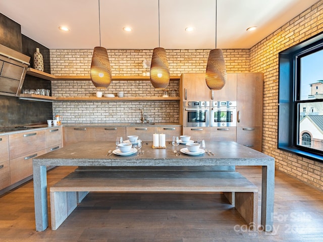 kitchen with stainless steel oven, brick wall, and a breakfast bar area