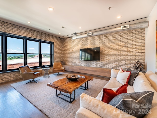 living room featuring brick wall and wood-type flooring