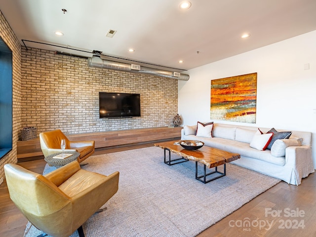 living room featuring brick wall and wood-type flooring