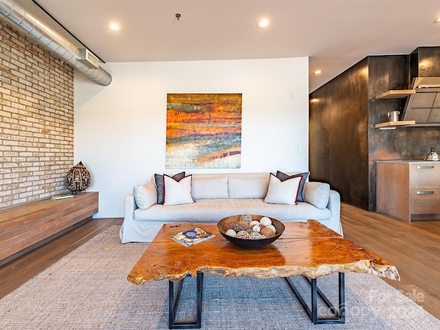 living room with wood-type flooring and brick wall