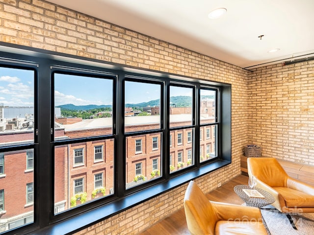 doorway to outside featuring hardwood / wood-style floors, brick wall, a mountain view, and plenty of natural light