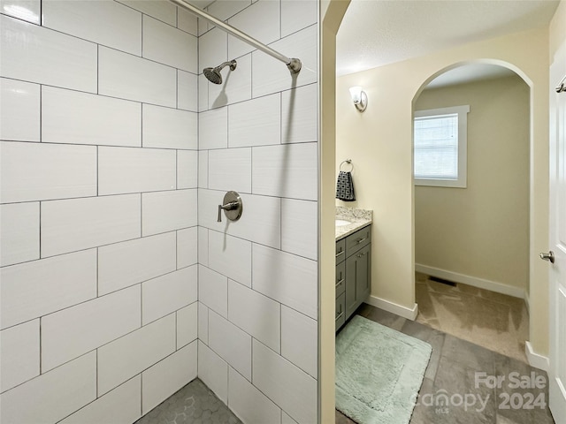 bathroom with tiled shower and vanity