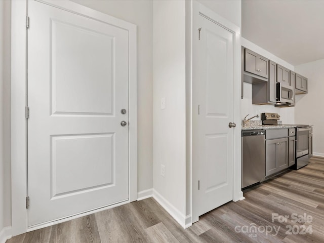 kitchen with gray cabinets, appliances with stainless steel finishes, and hardwood / wood-style flooring