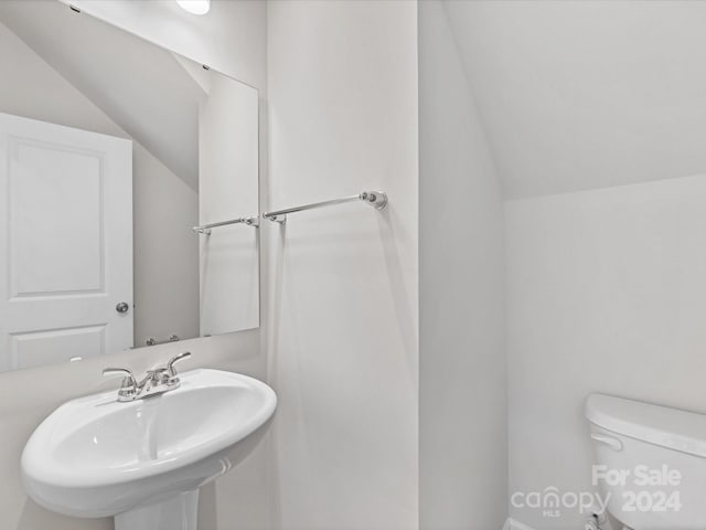 bathroom featuring sink, toilet, and vaulted ceiling