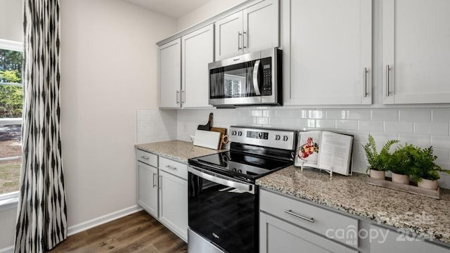 kitchen with stainless steel appliances, white cabinets, backsplash, and light stone counters