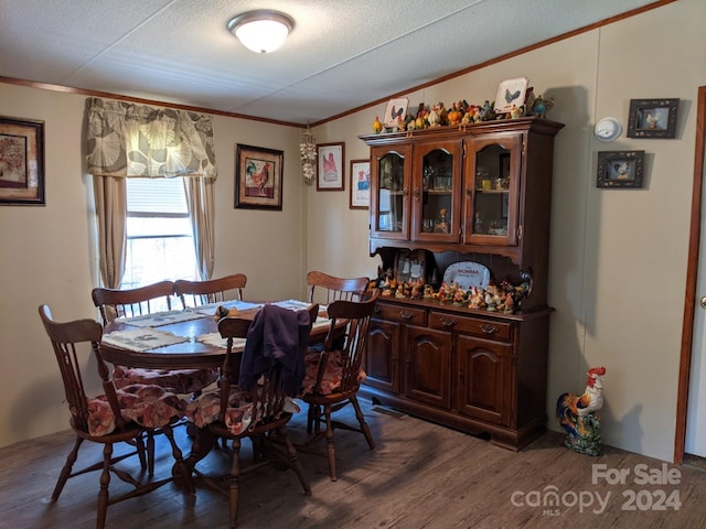 dining room featuring a textured ceiling, dark hardwood / wood-style flooring, and crown molding