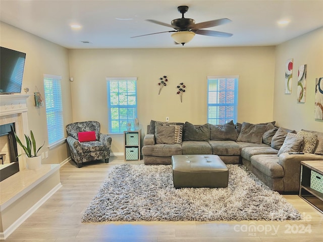 living room featuring a high end fireplace, ceiling fan, and light hardwood / wood-style floors