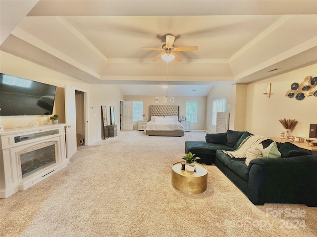 carpeted living room with ceiling fan and a tray ceiling