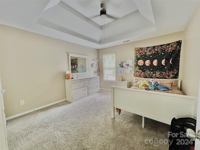 carpeted bedroom featuring ceiling fan and a tray ceiling