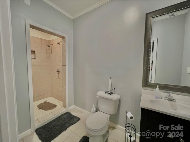 bathroom featuring vanity, tiled shower, tile patterned floors, crown molding, and toilet