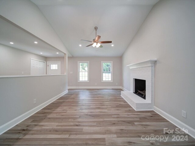 unfurnished living room with hardwood / wood-style flooring, a fireplace, high vaulted ceiling, and ceiling fan