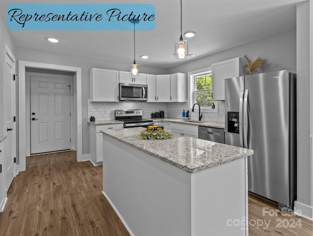 kitchen with a kitchen island, white cabinetry, stainless steel appliances, and hardwood / wood-style floors