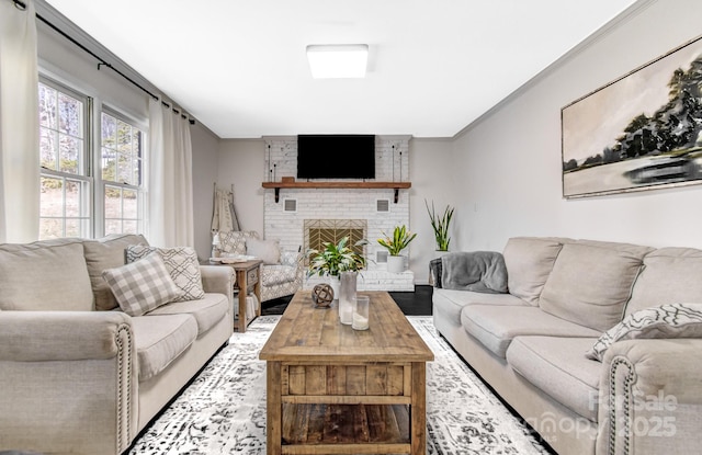 living room with a brick fireplace, crown molding, and wood finished floors