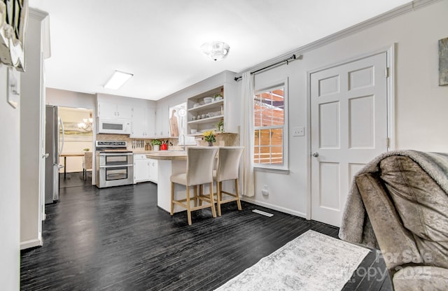 interior space with a breakfast bar area, stainless steel appliances, dark wood-type flooring, white cabinetry, and light countertops