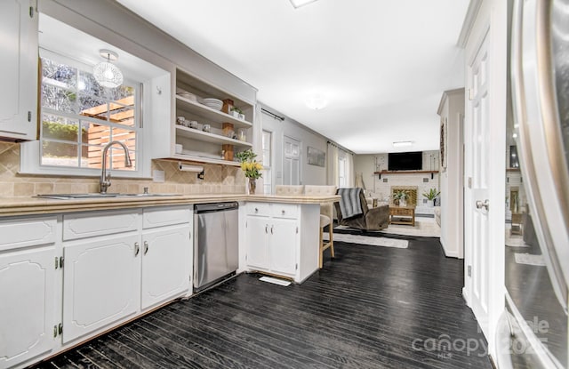 kitchen with white cabinets, a sink, light countertops, open shelves, and stainless steel dishwasher