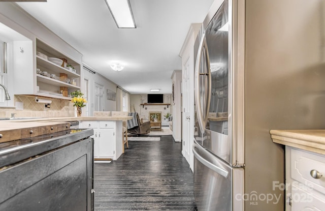 kitchen with white cabinetry, light countertops, backsplash, freestanding refrigerator, and dark wood finished floors