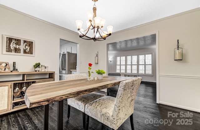 dining area featuring ornamental molding, dark wood-style flooring, and an inviting chandelier