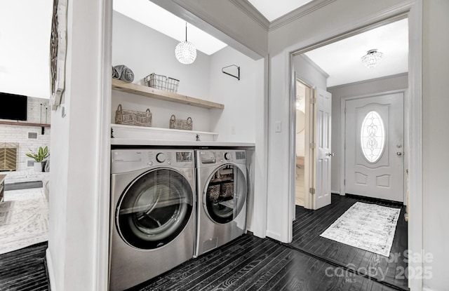 clothes washing area featuring laundry area, baseboards, dark wood-style floors, washing machine and clothes dryer, and crown molding