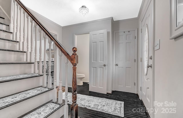 foyer entrance featuring dark wood-style floors, stairs, and ornamental molding