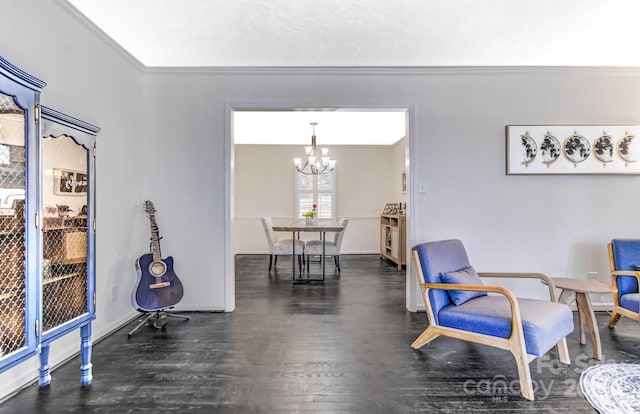 sitting room featuring a chandelier, ornamental molding, dark wood-style floors, and baseboards