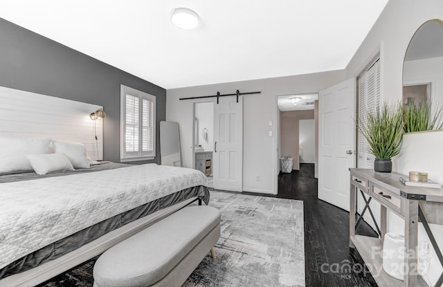 bedroom with dark wood-style floors, a barn door, and baseboards