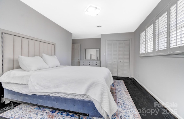 bedroom with dark wood-style floors, a closet, visible vents, and baseboards